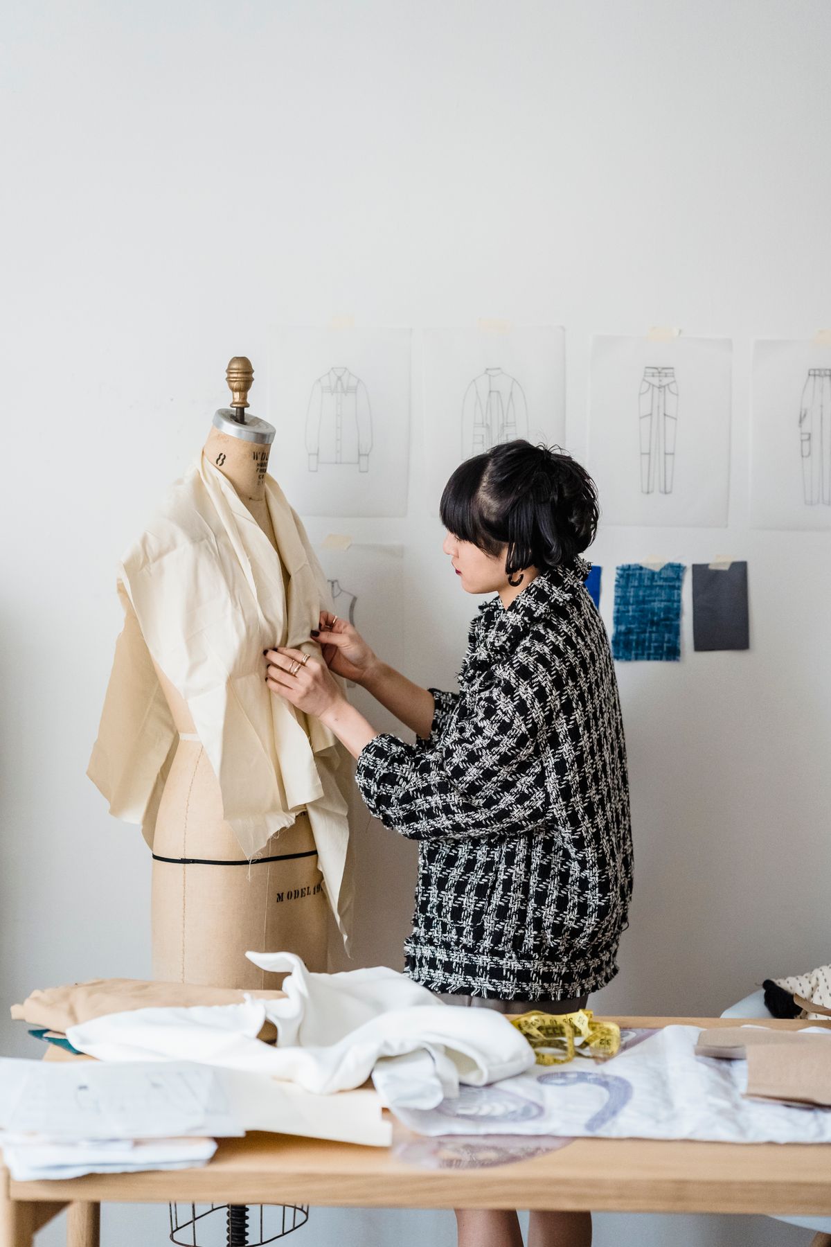 A person measuring fabric on a dress form in a sewing studio