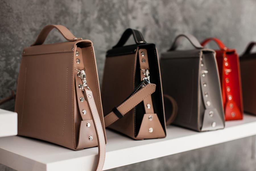 Leather handbags arranged on a white wooden shelf