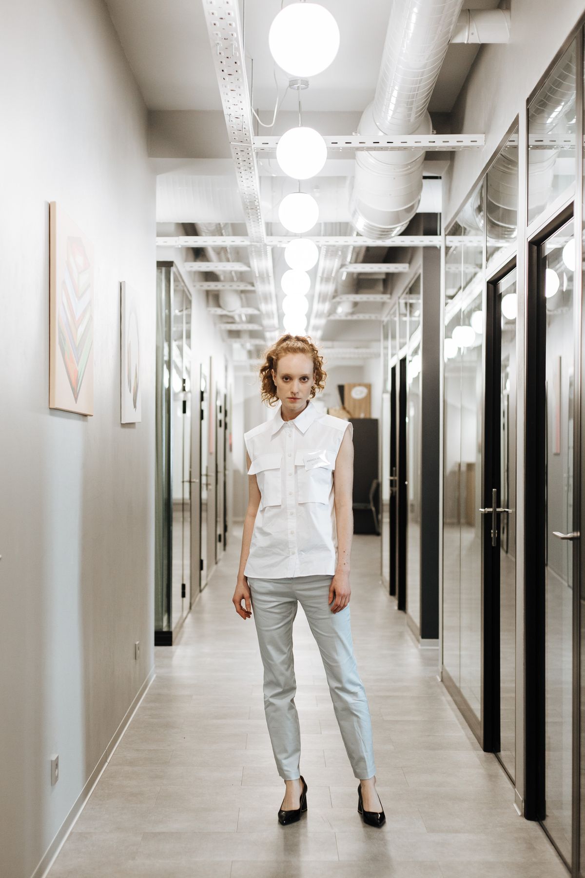A woman in tailored trousers standing in a bright office hallway